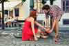 Loveandfriends man helping woman who has fallen off bike pick up groceries with a romantic spark between them